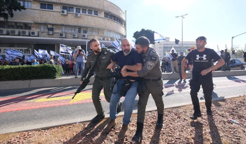 צלם הארץ רמי שלוש מעוכב בהפגנה בחיפה, הבוקר (צילום: פאדי אמון - צילום מסך מעיתון הארץ)